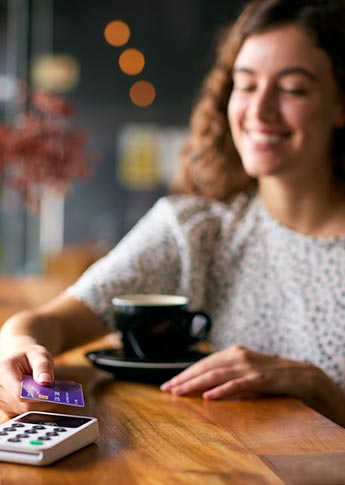 Young woman paying with credit card in cafe