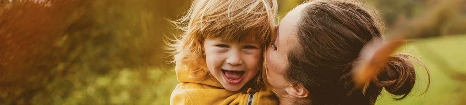 Mother hugging child outdoors.