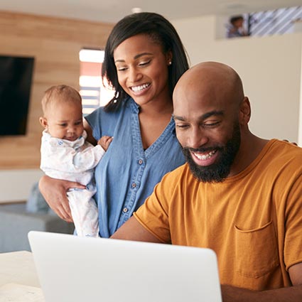 Young couple and baby using laptop in kitchen